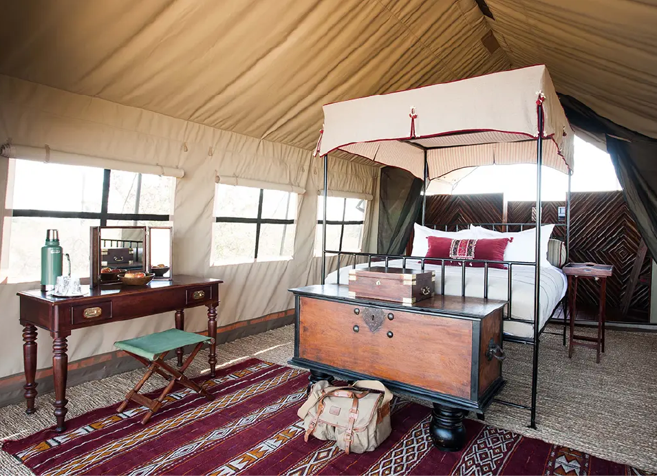 Comfortable safari tent accommodation in Botswana with a four-poster bed, wooden chest, and traditional furnishings