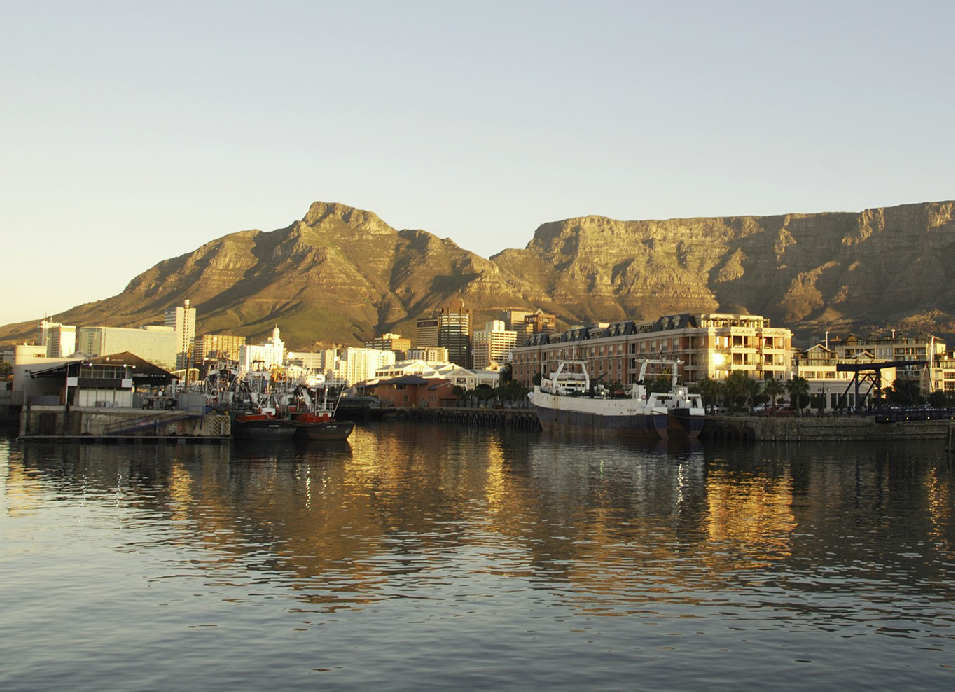 Cape Town waterfront with Table Mountain and the city skyline reflected in the water.