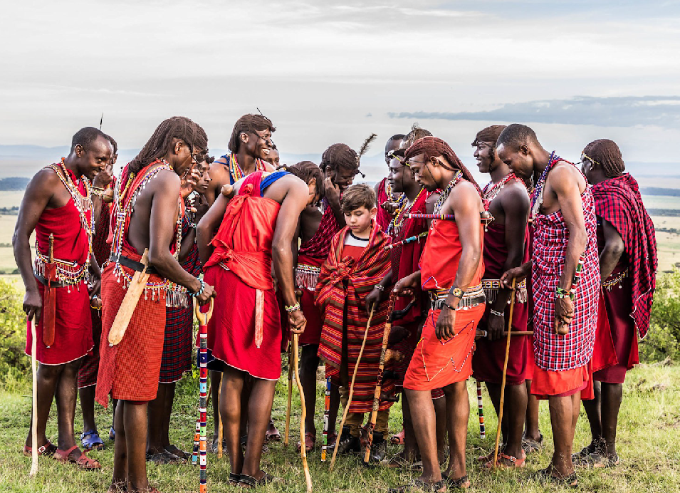 A group of Maasai people in traditional red clothing and colorful beaded jewelry gathered together in the Kenyan countryside.