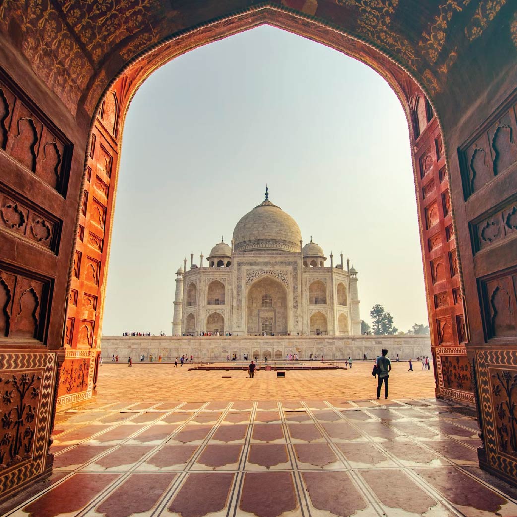 Taj Mahal in Agra, India, viewed from the front with its reflection in the surrounding water and gardens.
