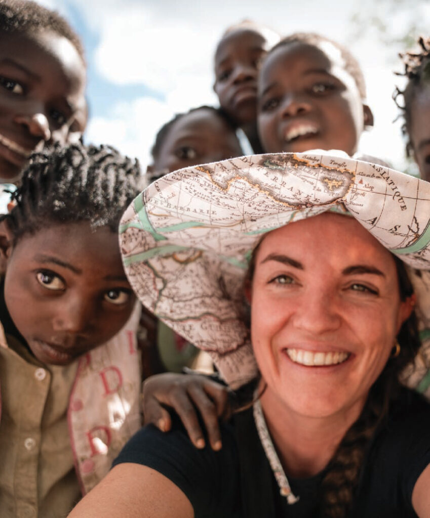 Woman smiling for a selfie with a group of children in Gorongosa, Mozambique.