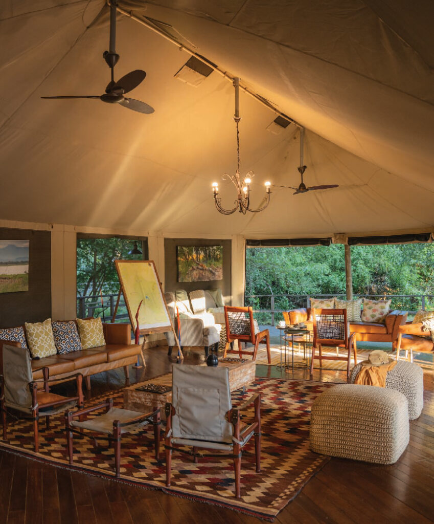 Elegant safari tent lounge with comfortable seating, ceiling fans, and views of the lush surroundings in Gorongosa, Mozambique