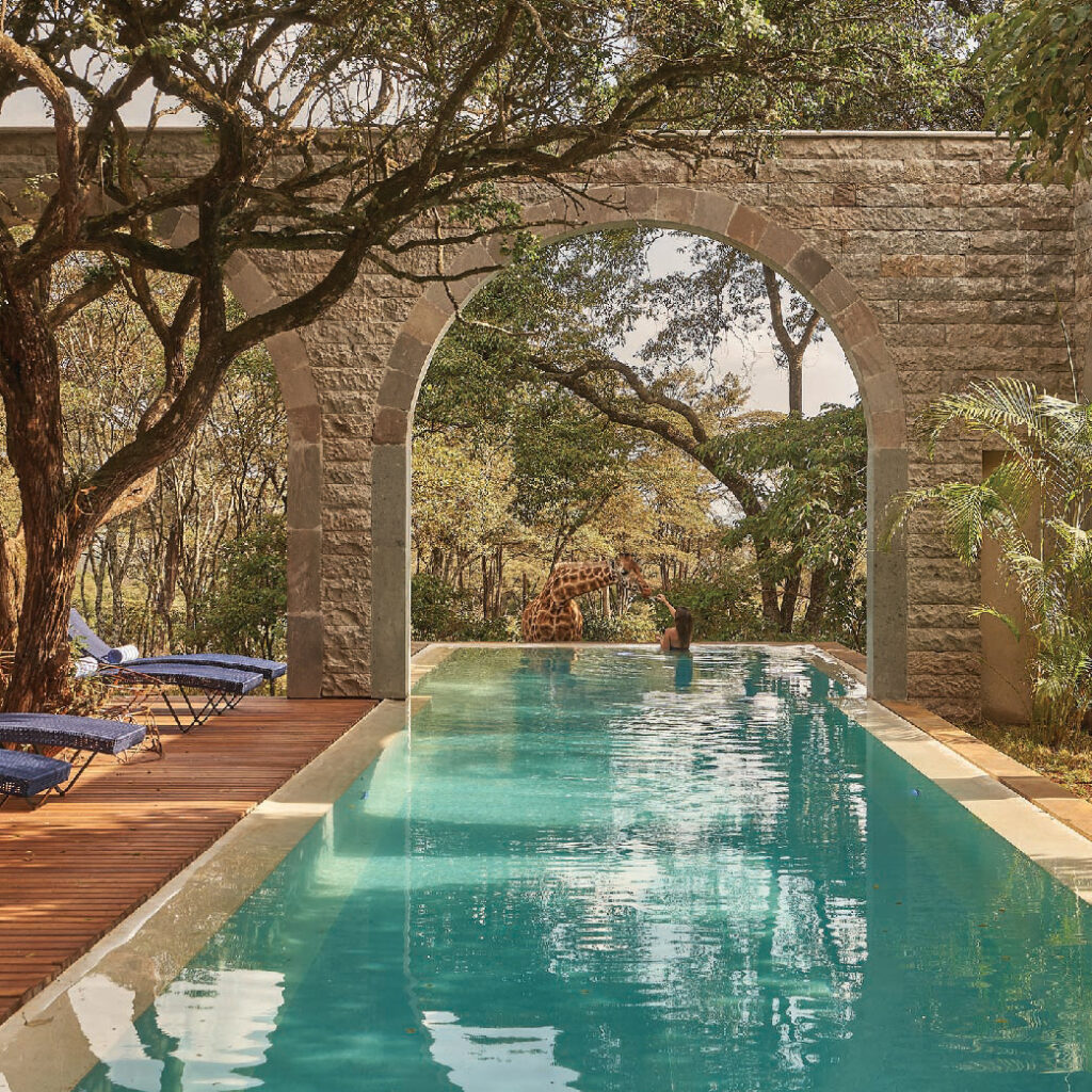 Luxury swimming pool surrounded by trees and stone arches at a safari lodge in Kenya