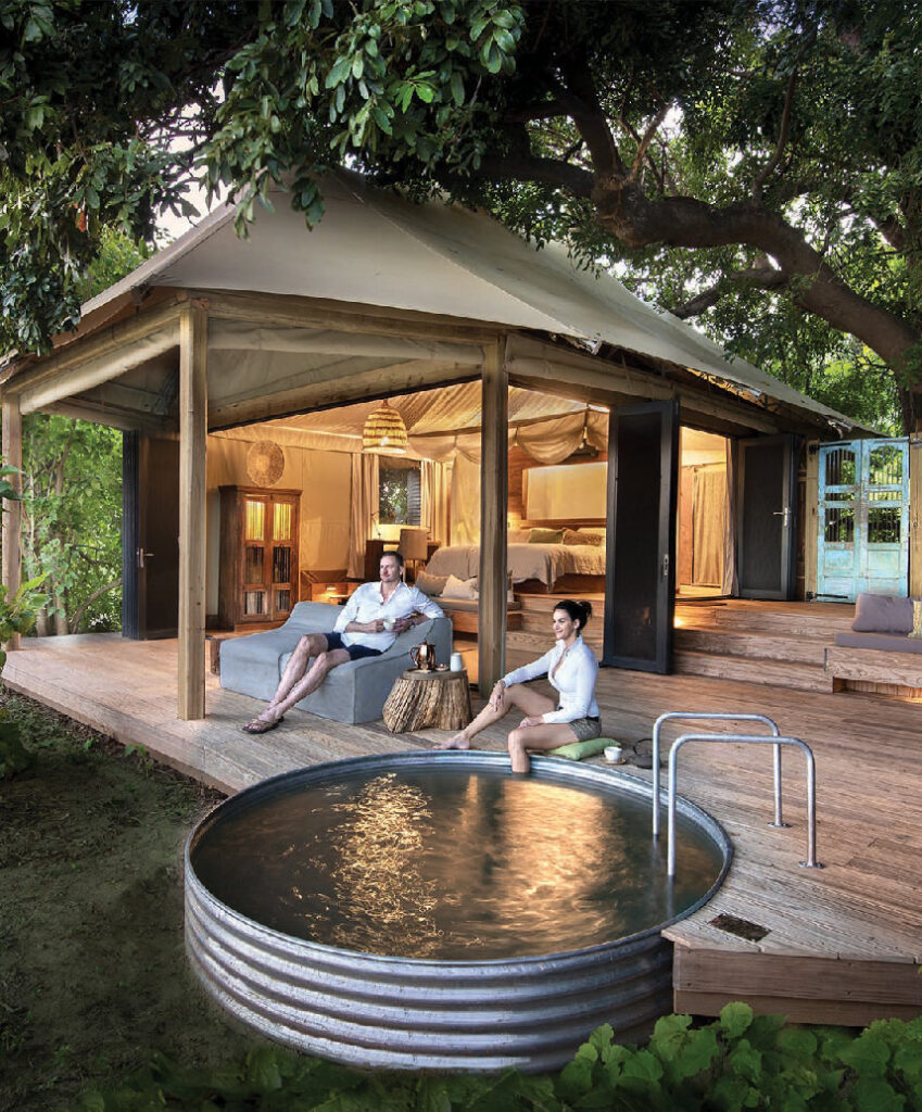 Guests relaxing on the wooden deck of Nyamatusi Lodge beside a private plunge pool, surrounded by lush trees in Mana Pools.