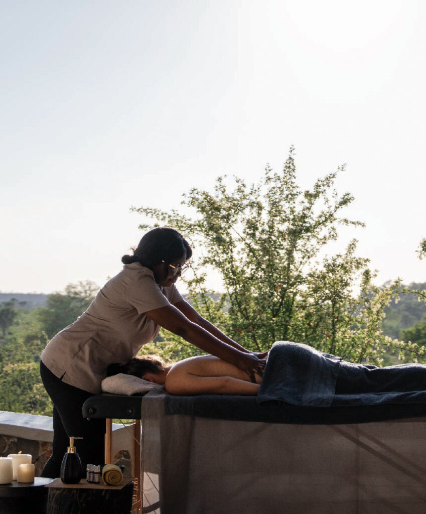 Massage therapist giving a relaxing outdoor massage to a guest at a safari lodge.