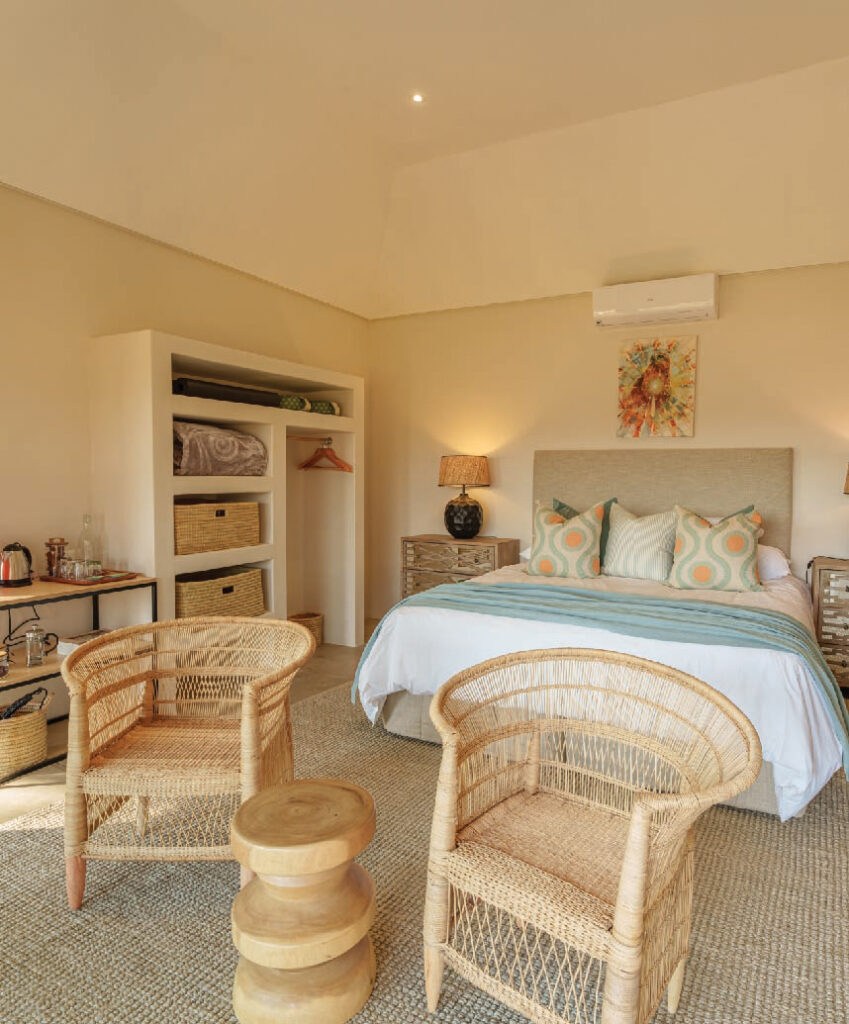 Bright safari lodge bedroom with a king-size bed, wicker chairs, and natural decor.
