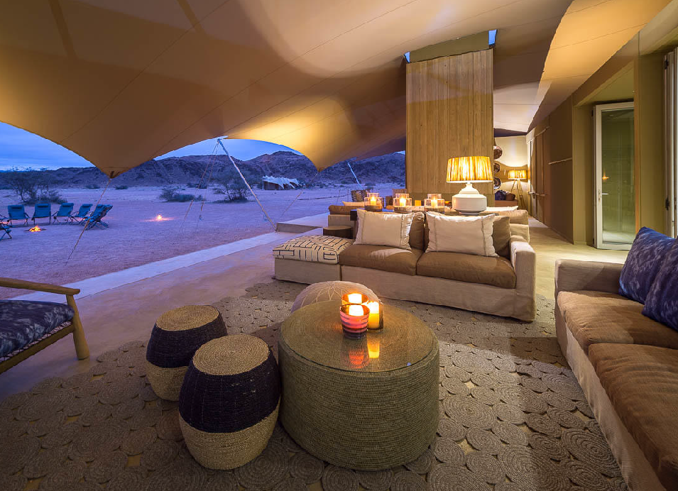 Luxury safari lodge lounge with comfortable seating overlooking the Namibian desert at dusk