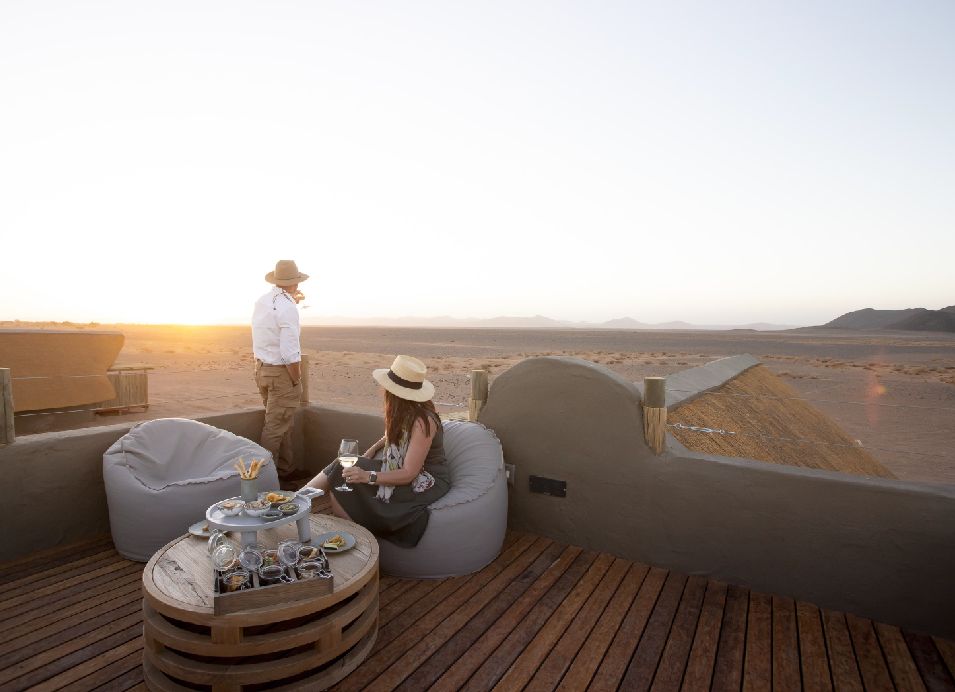 Couple enjoying drinks on a luxury desert safari lodge terrace at sunset in Namibia